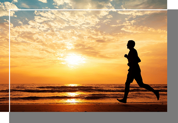 A man running on the beach at sunset.