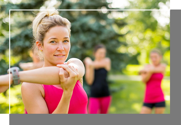 A woman in pink shirt and black shorts doing stretching exercises.