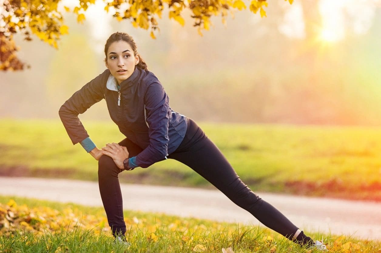 A woman stretching her legs in the grass.