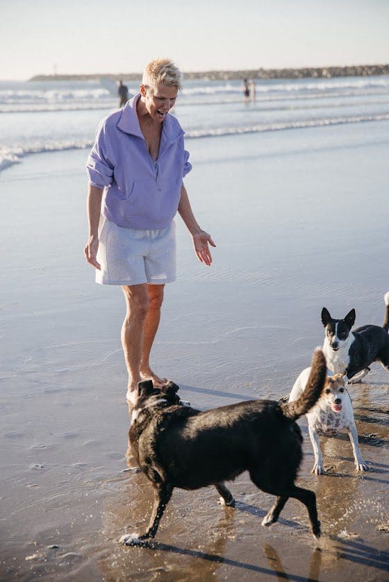 A woman walking on a beach with dogs.