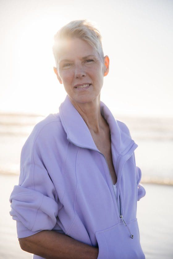 A woman standing on the beach in front of the ocean.