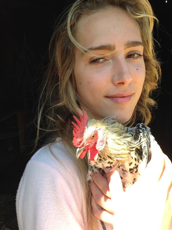 A woman holding a chicken in her hand.